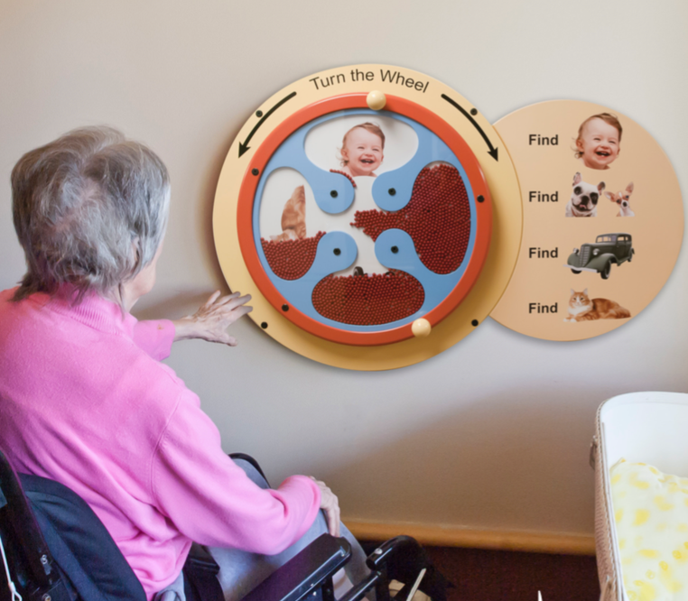 A wooden wheel mounted to a wall that has many beads and four sections. Each section contains a comforting image. When you turn the wheel, the beads will shift to reveal a picture. The four pictures are a baby, a pair of dogs, a car, and a cat