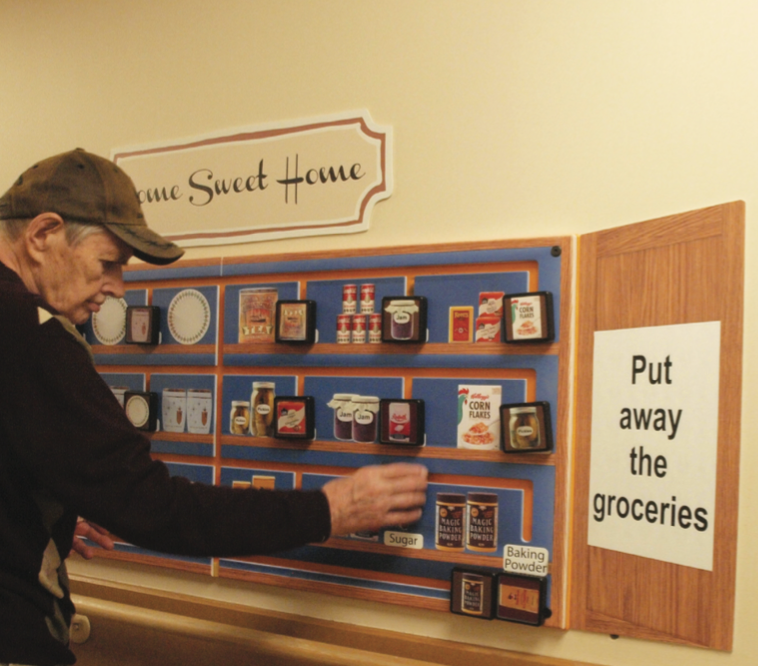 image of a filled kitchen cupboard mounted on a wall. Elderly man placing a physical item on the board where the image matches